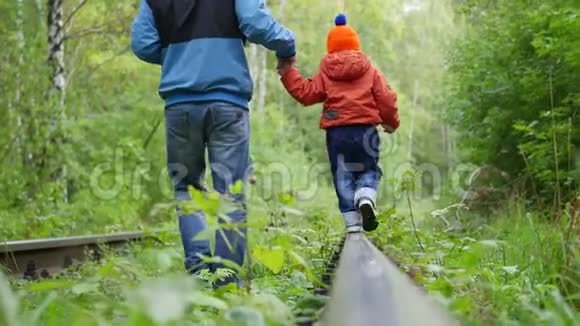 一个十几岁的男孩和他的弟弟和我父亲一起走在铁轨上危险的游戏和娱乐视频的预览图