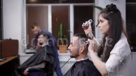 一个留着深色长发的女人原来是个理发师给理发店的顾客剪头发男人想视频的预览图