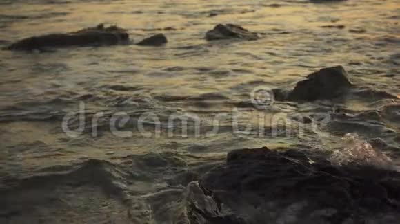 日落时在岩石上溅起小浪视频的预览图