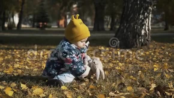 小孩子在秋天公园玩宝宝玩黄叶秋天公园户外的小女孩一幅肖像画视频的预览图