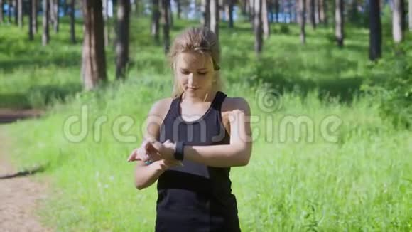 一个年轻的金发女人在智能手表上改变设置一个跑步的运动员想知道她有多少公里视频的预览图