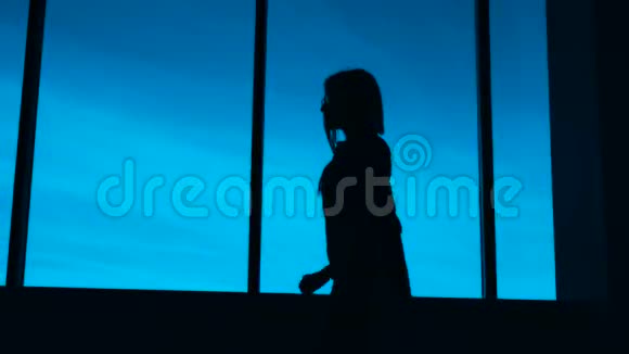 办公室女性剪影晚上站在办公室窗口的一个面目全非的女人的剪影视频的预览图