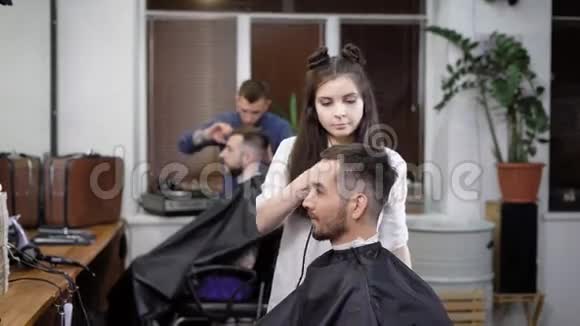 在理发店工作的男人和女人为坐在椅子上的顾客做时髦的头发视频的预览图