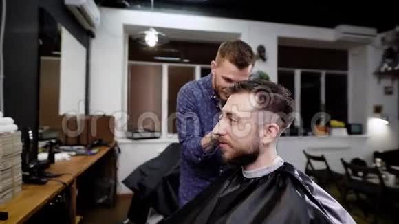 一个年轻人来到理发店是为了从一个专业的理发师那里得到时尚的发型和时尚的造型视频的预览图