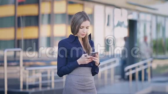 女商人在办公楼用电话年轻自信的女办公室职员站着浏览视频的预览图