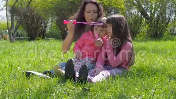 有肥皂泡的幸福家庭一个女人和女孩在新鲜空气中玩耍公园里有妈妈的小女孩视频的预览图