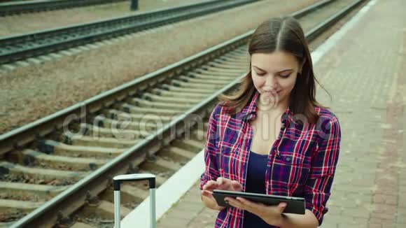 年轻女子在火车站用平板电脑概念网上机票热爱旅游视频的预览图
