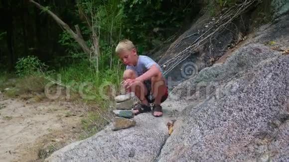 一个年轻人用平衡的石头做雕塑户外运动视频的预览图