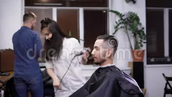 一位时尚年轻的女理发师手里拿着一个修发师开始做发型和发型视频的预览图