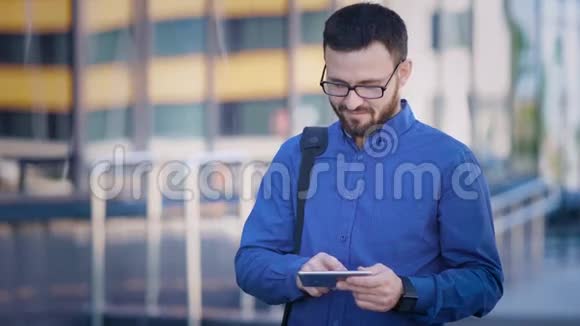 开朗的男人在办公室浏览智能手机在办公楼使用智能手机的满脸胡须的上班族视频的预览图