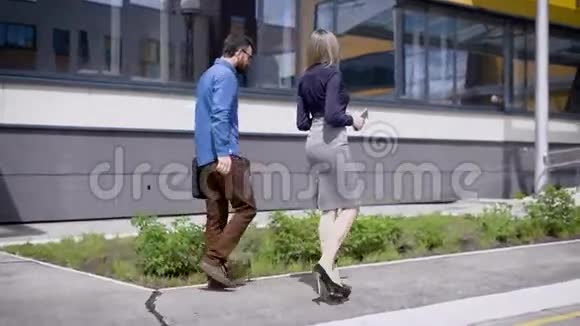 办公大楼的商务人员城市办公室附近的商务男女步行和交流的背面视图视频的预览图