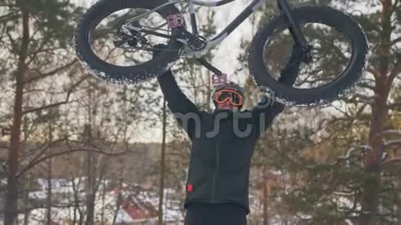 专业的极限运动员骑自行车在户外骑胖自行车上山骑自行车的人走在冬天的雪林里男子视频的预览图