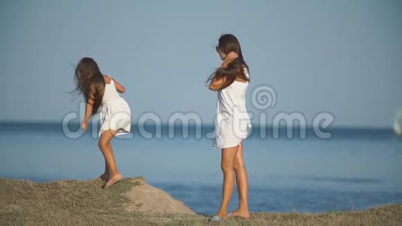妈妈带着女儿穿着白色裙子靠近大海视频的预览图
