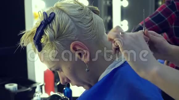 美容院理发店发型师理发师给年轻女孩理发造型师用剪刀和梳子特写镜头视频的预览图