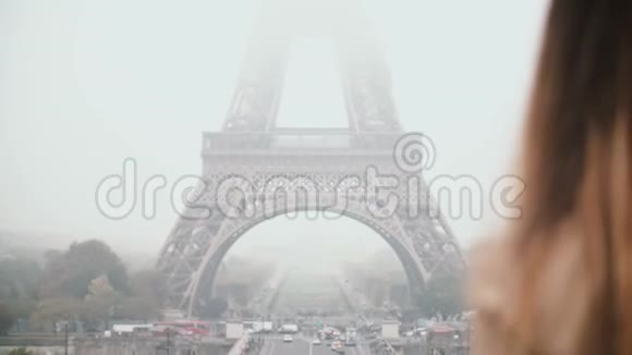 年轻漂亮的女人走在市中心附近的埃菲尔铁塔在巴黎法国并通过手机交谈视频的预览图