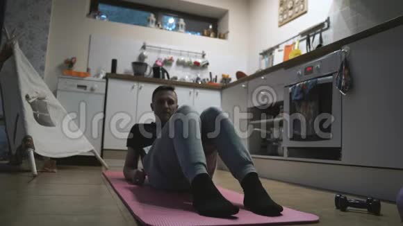 在家的厨房里进行英俊的男子锻炼和俯卧撑视频的预览图