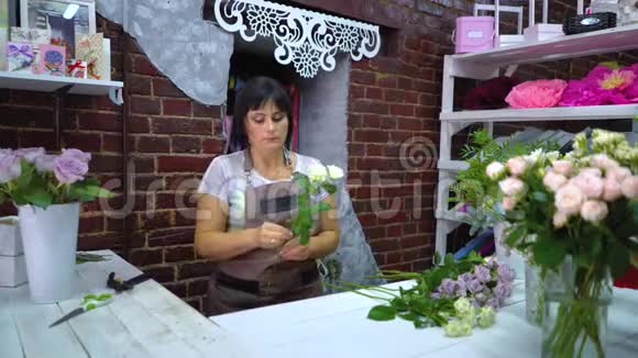 专业花店清洁和检查干花瓣上的白玫瑰枝视频的预览图