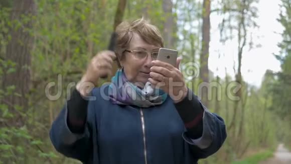 一位年长的美女看着一部智能手机带来美丽梳头调整衣服去散步视频的预览图