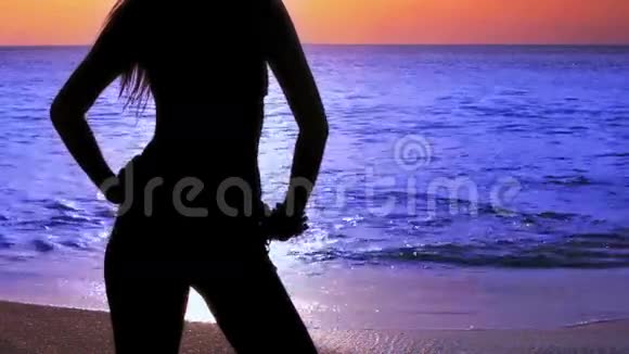 日落时海滩上神秘的剪影女孩视频的预览图