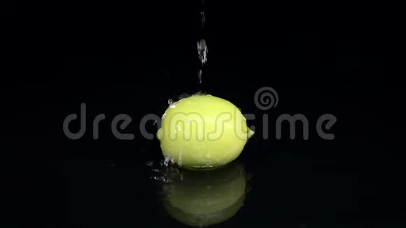 柠檬在水中一滴纯净的水从上面倒在上面黑色背景慢动作视频的预览图