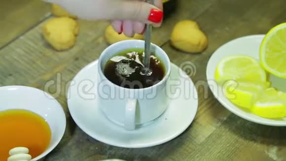 女人在木桌上的白色杯子里搅拌勺子新鲜冲泡的红茶视频的预览图