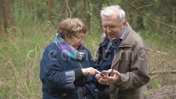 一对老夫妇在智能手机上看孙辈的照片微笑和欢笑体验快乐彼此相爱视频的预览图
