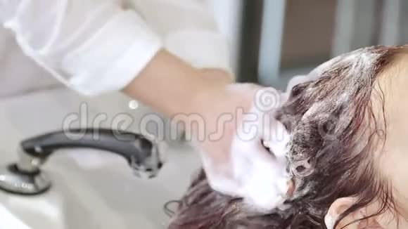 理发师在美容院用洗发水轻轻地清洁头发视频的预览图
