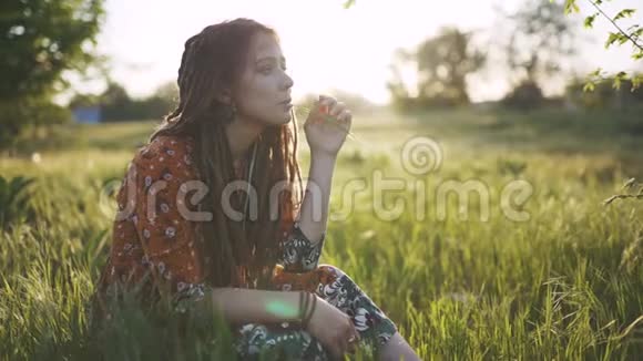 美丽的嬉皮士女人在日落时带着绿草中的可怕的怪物在户外玩得很开心视频的预览图