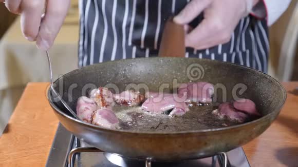 在餐厅的一个热煎锅上加入肝片的厨师烹饪弗拉姆贝式菜肴用勺子搅拌视频的预览图
