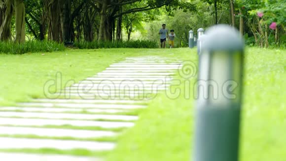 亚洲的父亲夏天在公园慢动作地跟在儿子后面跑视频的预览图