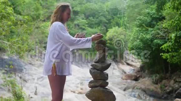 一个女孩做一个岩石平衡的雕塑户外运动视频的预览图