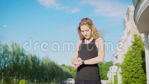 年轻女运动员跑街后用手表检查脉搏视频的预览图