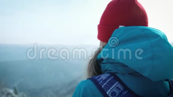 年轻的女游客在冬天在智能手机上拍照拍摄雪山的照片视频的预览图