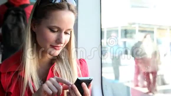 坐在电车上的金发女郎用手机打字电话手机视频的预览图