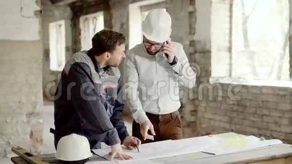 现场工人制定项目计划两个戴着安全帽的人在做新的项目计划主管在打电话视频的预览图