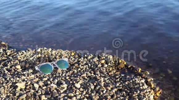 带镜子的太阳镜躺在鹅卵石滩上视频的预览图