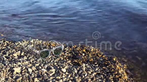带镜子的太阳镜躺在鹅卵石滩上视频的预览图