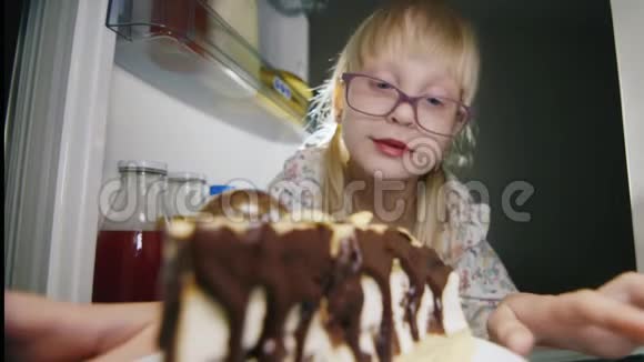 幼稚恶作剧一个戴着粉红色眼镜的小女孩偷偷地咬了冰箱里的巧克力蛋糕甜蜜的情人有趣搞笑视频的预览图
