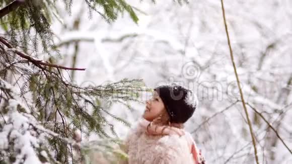 一个快乐的女学生从树上刷雪冰雪覆盖的公园降雪圣诞节假期视频的预览图