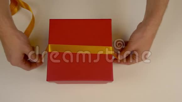 准备礼品包装一个红色的纸板箱男士双手测量金色缎带装饰礼品盒视频的预览图