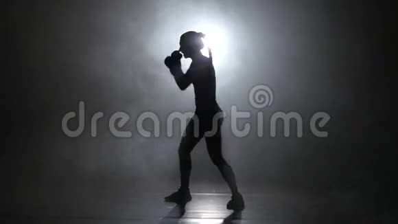 冠军拳手发出拳打脚踢剪影后方有灯光黑色背景侧视图视频的预览图