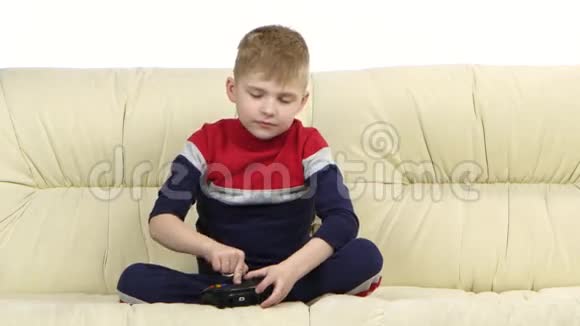 带游戏机的小男孩在沙发上玩电子游戏视频的预览图