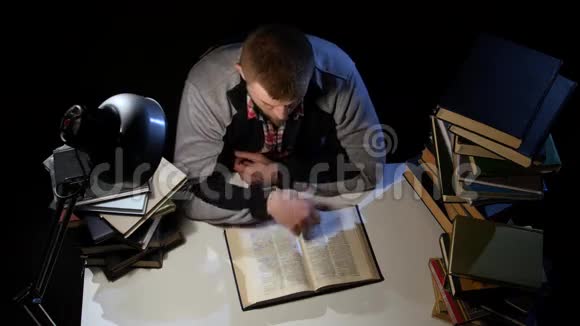 男人翻阅着书睡着了黑色背景从上面看视频的预览图