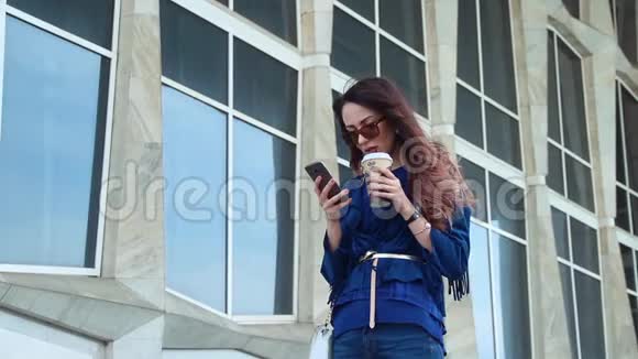 在商业区喝咖啡和使用智能手机的年轻女性视频的预览图
