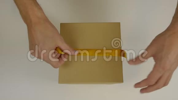 准备送礼物礼盒包装用金丝带双手用黄色丝带包裹礼品盒视频的预览图