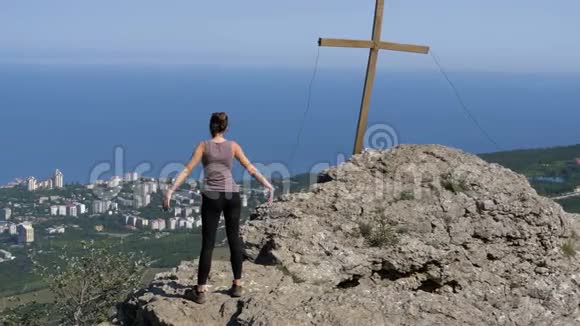 女人练习瑜伽动作带十字架的悬崖顶部视频的预览图