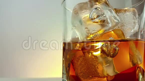 在杯中加入冰块在温暖的白色背景下加入酒保倒入威士忌放松时间与威士忌视频的预览图