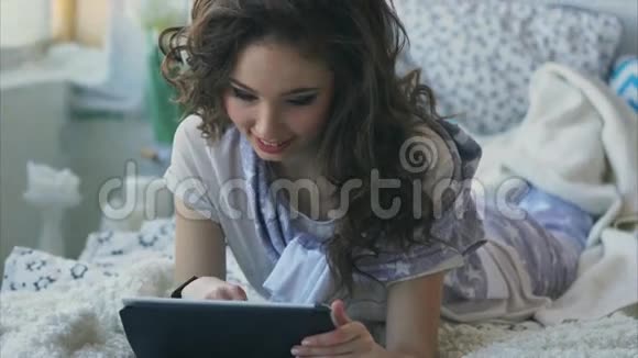 可爱的女人在便携式平板电脑上与社交网络中的朋友交谈视频的预览图