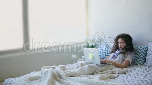 漂亮的女人躺在床上早上在笔记本电脑上工作视频的预览图
