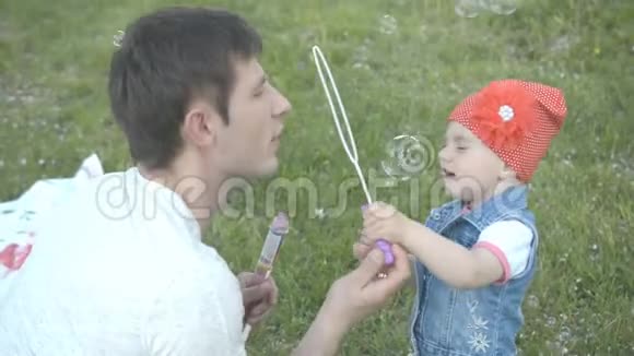 父亲和女儿在草地上的公园里玩耍视频的预览图